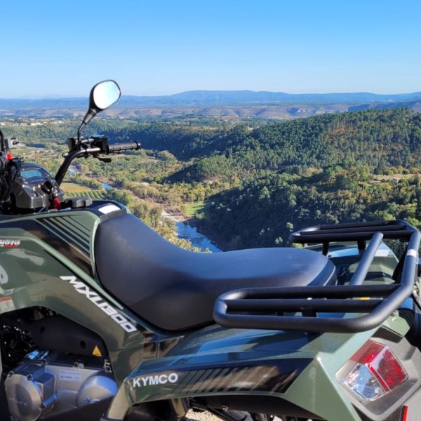 un quad à l'arrêt sur un point de vue, avec au fond les montagnes ardéchoises et les cévennes